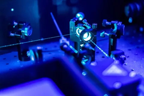 Blue lasers reflect on an optic table.