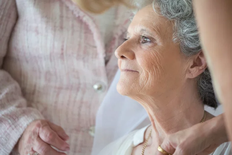 Two people care for an older woman.