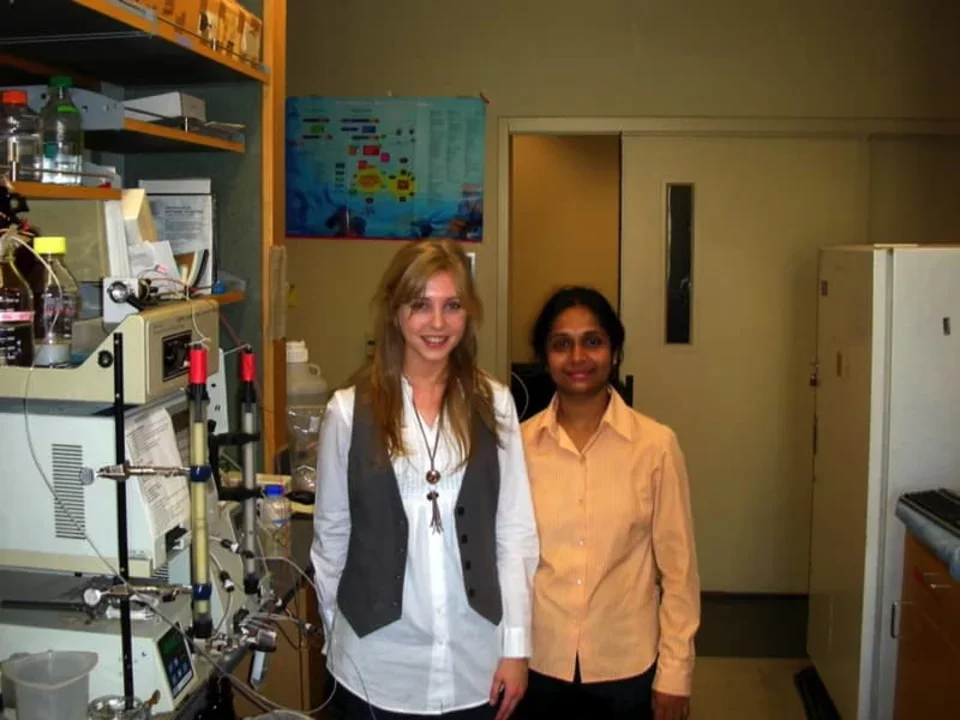 Two researchers stand in the Bitan Lab with equipment visible to their left.