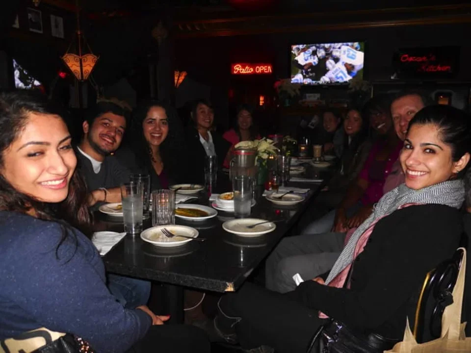 Bitan Lab members sit at a long rectangular dinner table in a dimly lit restaurant.