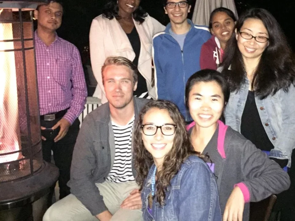 Lab members huddle around an outdoor heat lamp to stay warm during a group outing.