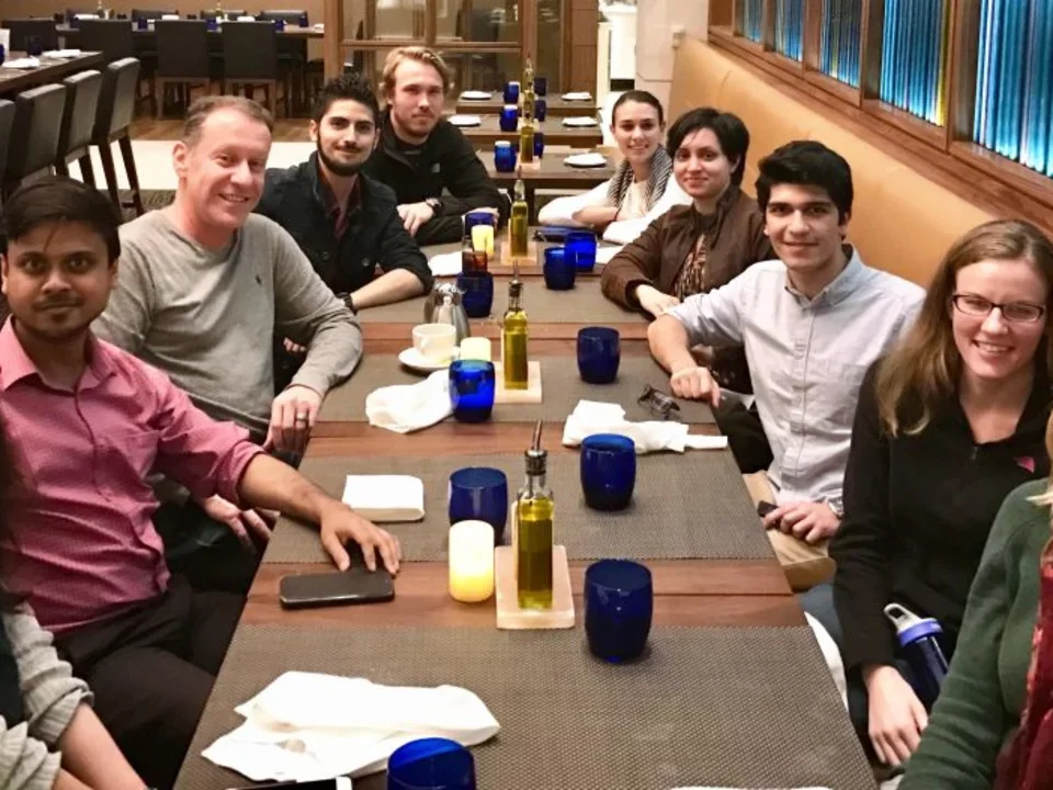 The group sits at a long rectangular table during a dinner outing.