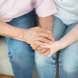 A couple comforts each other by holding hands.