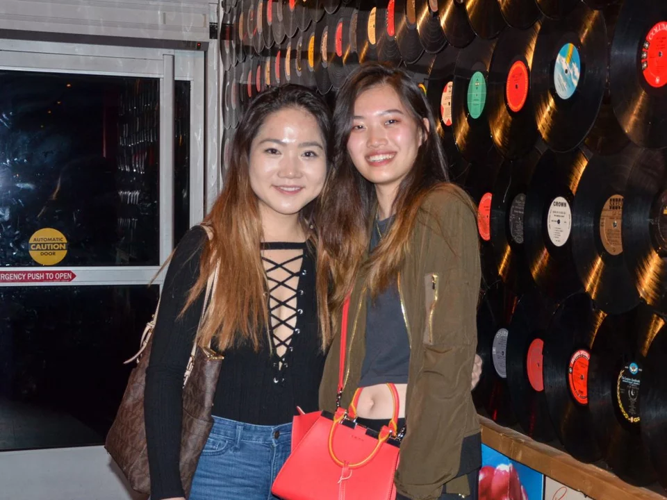 Two students stand in front of a wall with LP records on display.
