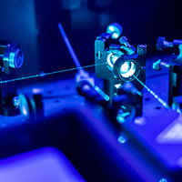 Blue lasers reflect on an optic table.